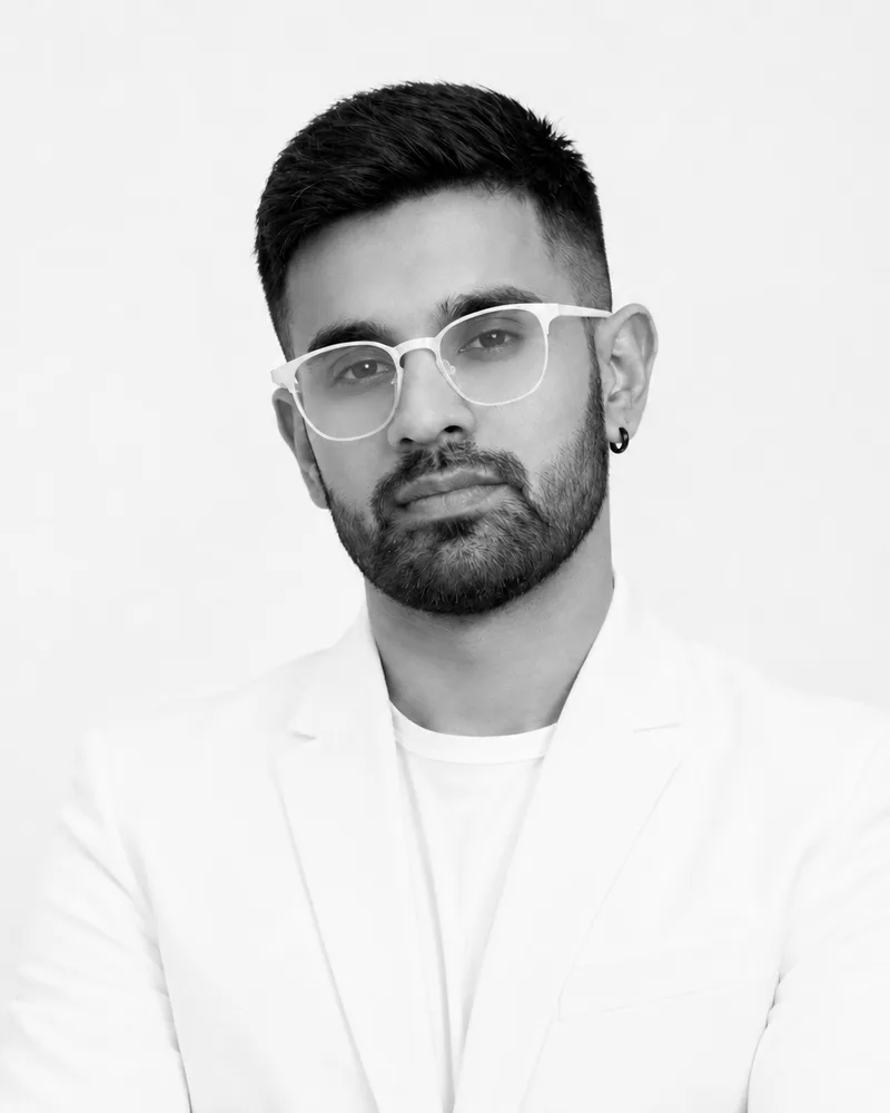 Faizan, co-founder and creative director of Creative Frog, in a white blazer and clear-framed glasses